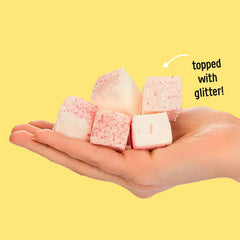 Keto Store NZ | Max Mallow | Marshmallows | Birthday Cake flavour with collagen and MCT oil | Keto Paleo GF | Hand holding pink and white marshmallows with glitter on a yellow background
