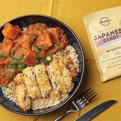 Keto Store NZ | Japanese Curry | Mingle Recipe Mix | Bowl of Japanese curry with breaded chicken and sweet potatoes on a yellow tablecloth, next to a Mingle Japanese Curry package.